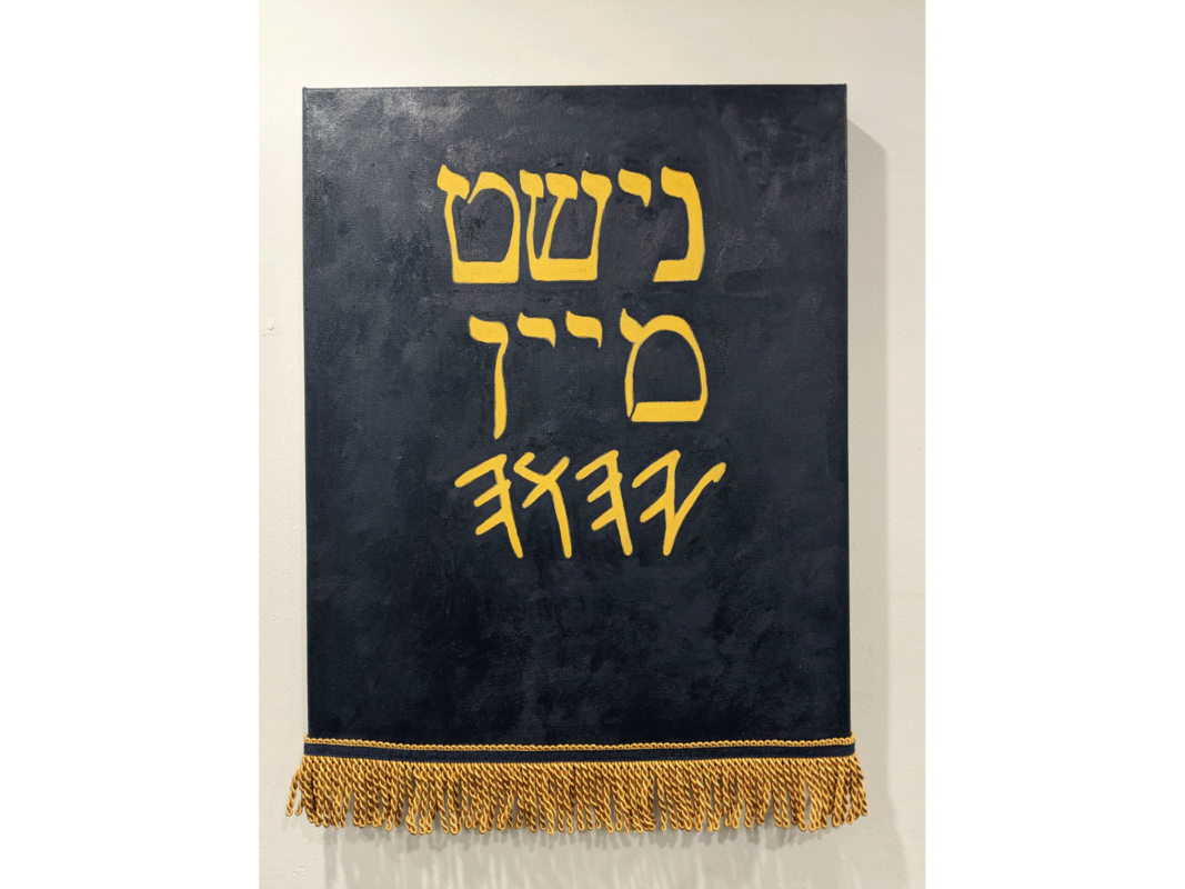 The artwork titled "Not My God" was created in 2020 by Goldie Gross. The artwork is an oil painting with Israelite fringes on canvas. Gold Hebrew letters that spell "Nisht mayn got" or "Not my God" are centered on a black background on a rectangular canvas, 20 inches tall and 16 inches wide.